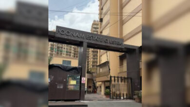 Entrance to Poonam Estate Cluster in Mumbai with high-rise buildings in background.