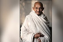 Mahatma Gandhi in traditional attire, sitting and smiling, reflecting on films he watched.