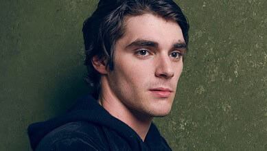 RJ Mitte, actor from Breaking Bad, with dark hair and serious expression against green background.