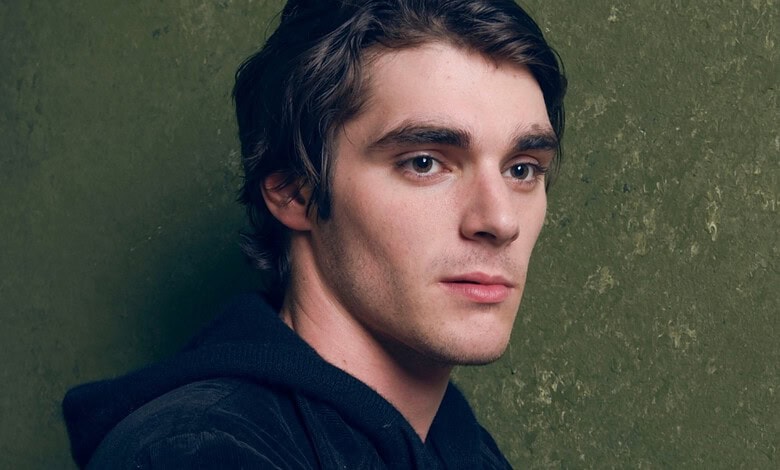 RJ Mitte, actor from Breaking Bad, with dark hair and serious expression against green background.