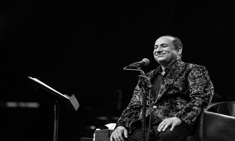 Rahat Fateh Ali Khan smiling while singing into a microphone during a live performance.