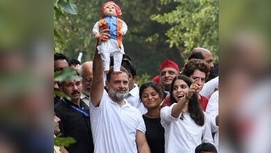 Indian politician Rahul Gandhi holding a doll during a public gathering or rally.