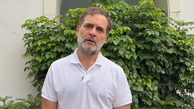 Rahul Gandhi speaking outdoors with greenery in the background.
