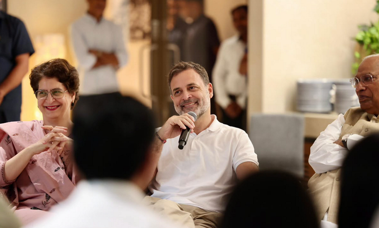 Rahul Gandhi speaking at a public event with smiling attendees around him.