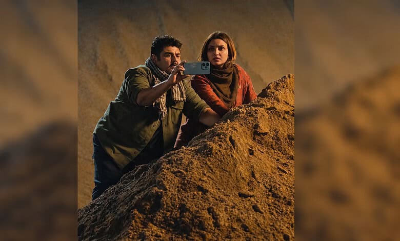 Two actors filming a scene on a rocky set for a drama production.