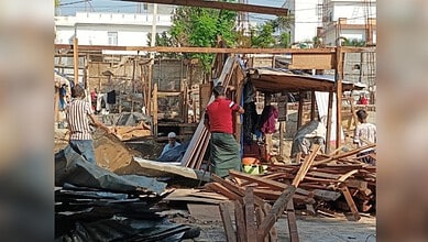 People working amidst construction debris and wooden structures in an outdoor setting.