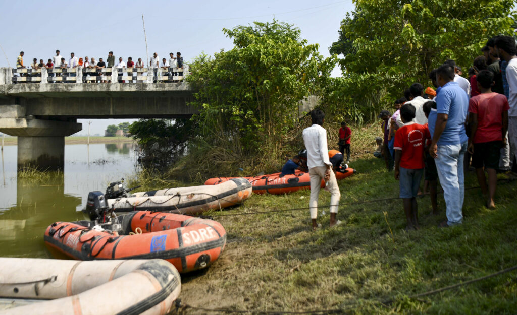 Rescue operation at riverbank after boat capsized in Bihar, with rescue boats and crowd present.