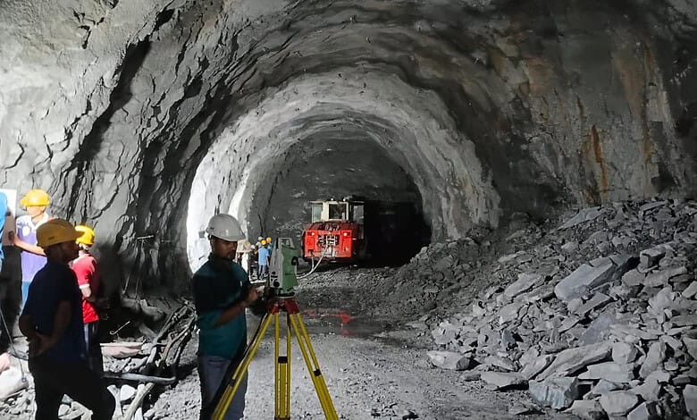 Workers and machinery inside a large underground mining tunnel under construction.