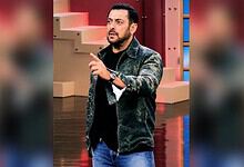 Salman Khan on Bigg Boss 20 set, wearing a black jacket and jeans, gesturing with his hand.