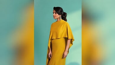 Elegant woman in yellow dress with earrings against green background.
