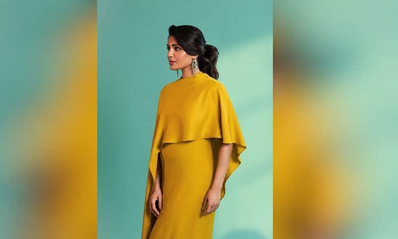 Elegant woman in yellow dress with earrings against green background.