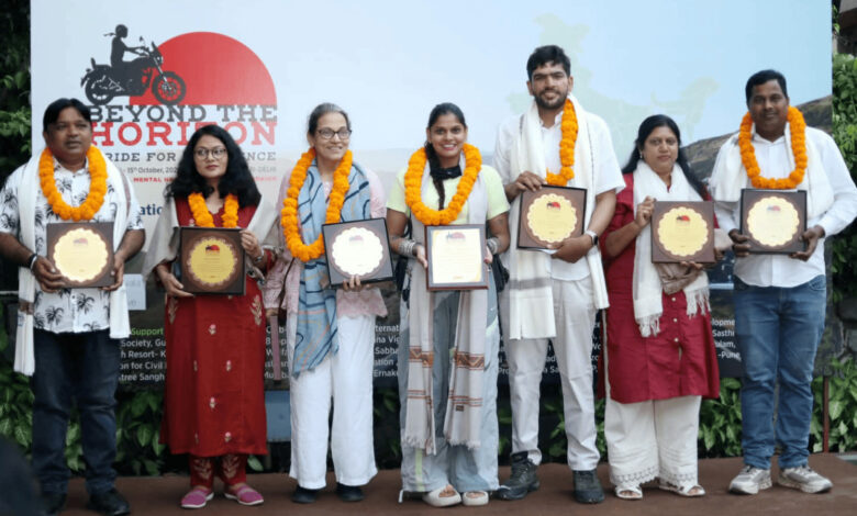 Group of people with marigold garlands holding awards at a mental health event.