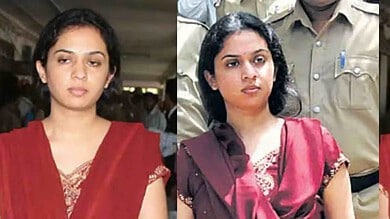 Two women in sarees at a public event, one in red and the other in maroon, with serious expressions.