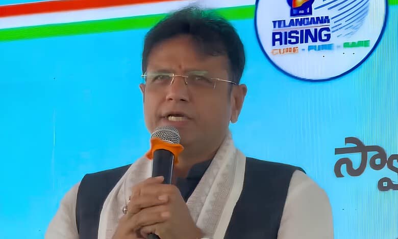 Sridhar Babu speaking at a public event with a microphone in hand.
