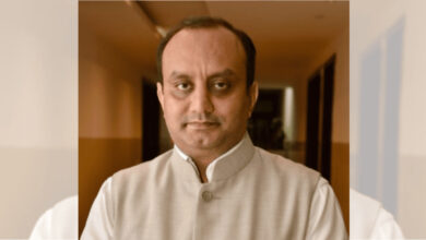 Indian man in traditional attire with a neutral expression, indoor setting.