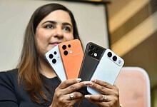 Woman showcasing four OPPO F35 smartphones in different colours at launch event.