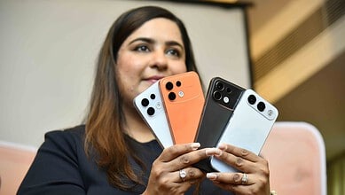 Woman showcasing four OPPO F35 smartphones in different colours at launch event.