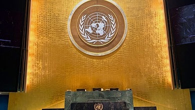 United Nations emblem displayed on a golden wall at the UN headquarters.