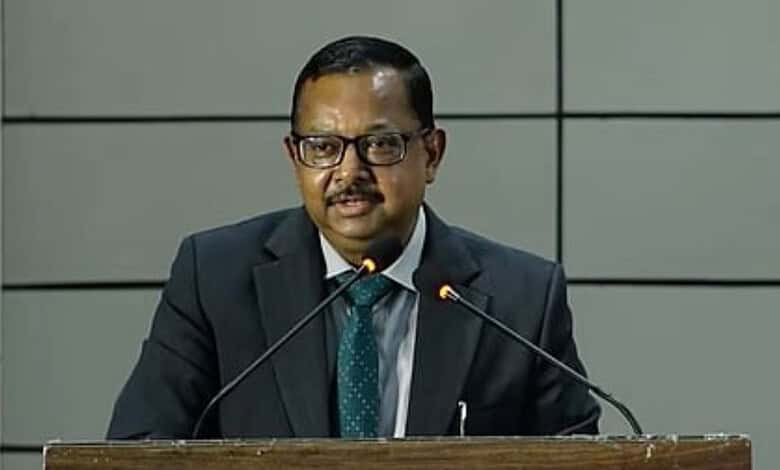 Man in suit speaking at a podium during a formal event or press conference.