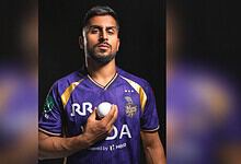 Cricketer Umran Malik in a purple jersey holding a cricket ball, looking serious.