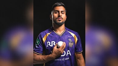Cricketer Umran Malik in a purple jersey holding a cricket ball, looking serious.
