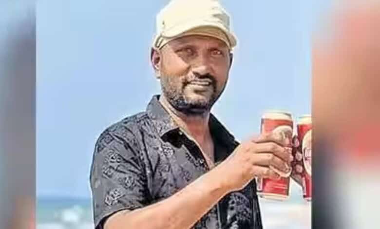 Man holding two cans of beverage outdoors with a blue sky background.
