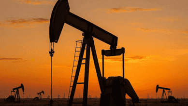 Oil pumpjacks operating at sunset in an oil field with a vibrant orange sky.