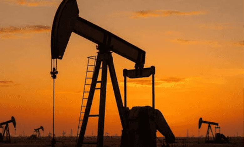Oil pumpjacks operating at sunset in an oil field with a vibrant orange sky.