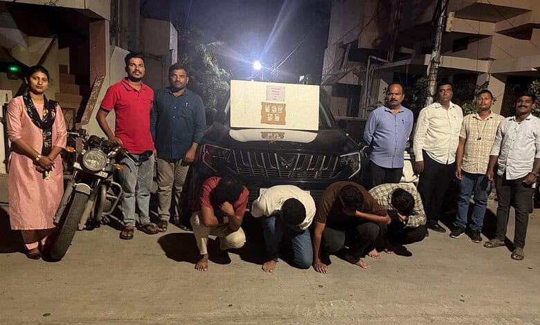 Group of people standing and kneeling in front of a vehicle at night.