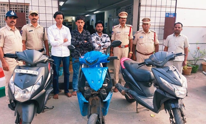 Group of police officers and civilians standing with three scooters outside a building.