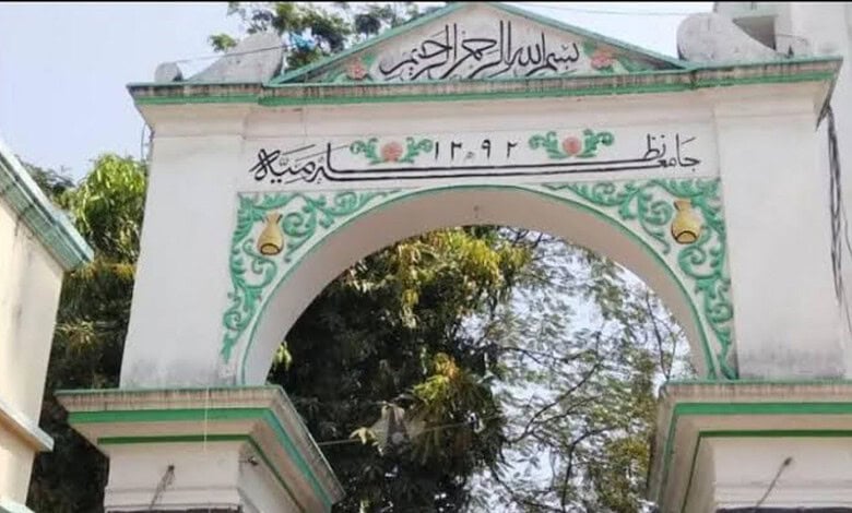 Archway with Arabic calligraphy and decorative green and yellow patterns in a garden setting.