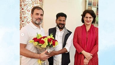 Three people, two men and a woman, smiling with a bouquet of flowers in a room.