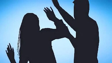 Silhouette of a man hitting a woman during a confrontation against a blue background.