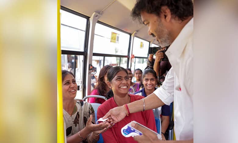 Man giving a free bus ticket to smiling women passengers on a bus.