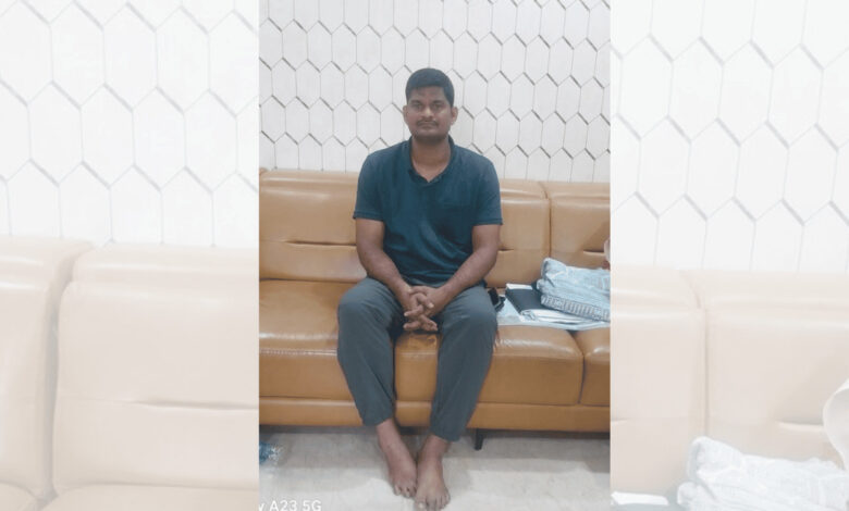 Young man sitting on a brown sofa in a modern room with white hexagonal wall tiles.