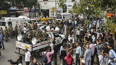 Protesters gather at Jantar Mantar with police barricades and vehicles present.