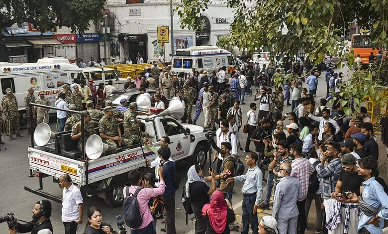 Protesters gather at Jantar Mantar with police barricades and vehicles present.