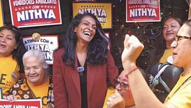 Indian-American women celebrating at a political event with Nithya banners in the background.