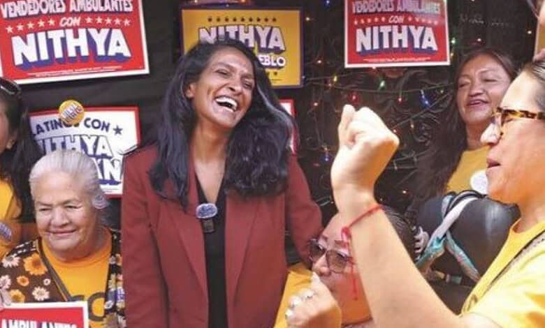 Indian-American women celebrating at a political event with Nithya banners in the background.