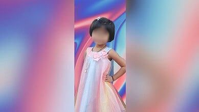 Young girl in a colourful dress standing with hand on hip against vibrant background.