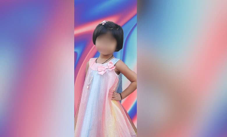 Young girl in a colourful dress standing with hand on hip against vibrant background.