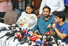 Gyanesh's supporters and family members at a press conference with microphones and media present.