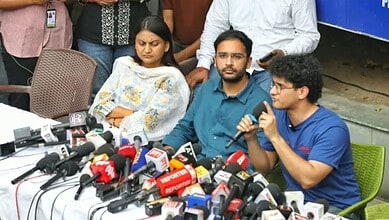 Gyanesh's supporters and family members at a press conference with microphones and media present.