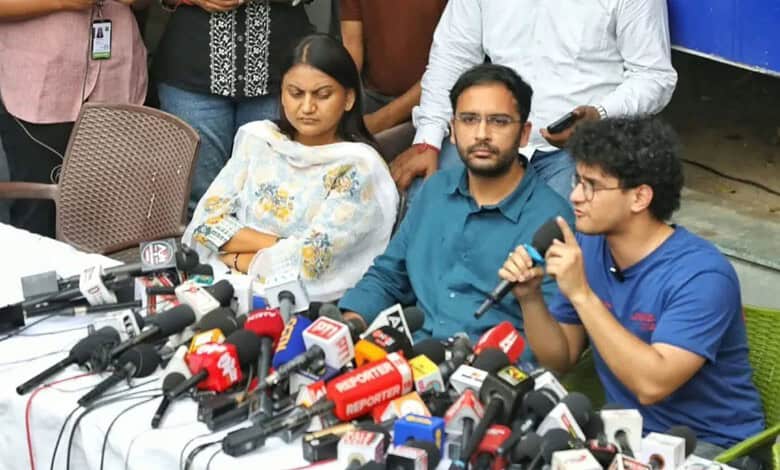 Gyanesh's supporters and family members at a press conference with microphones and media present.