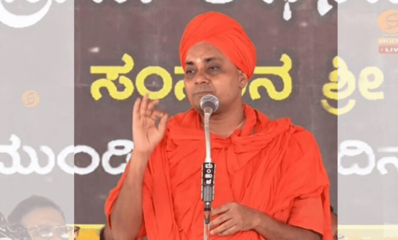 Gavisiddheshwara Swamiji speaking at Mysuru Dasara event in traditional orange attire.