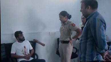 Delhi Police officers interrogate a man with a bloodstained shirt in a police station.