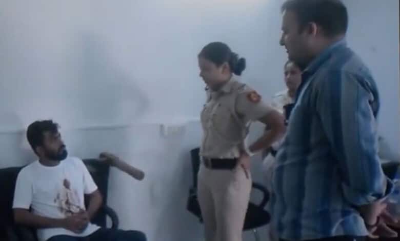 Delhi Police officers interrogate a man with a bloodstained shirt in a police station.