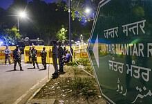 Jantar Mantar Road sign in Delhi with police officers and vehicles in the background.