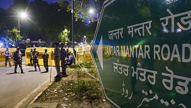 Jantar Mantar Road sign in Delhi with police officers and vehicles in the background.