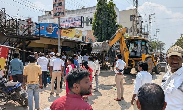 Road clearing operation with excavator and crowd on Moinabad–Chevella Road.